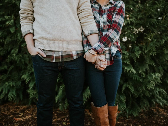 A couple holds hands while standing in a forest