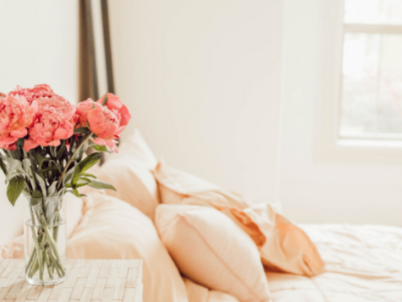 A bed with flowers on a table nearby