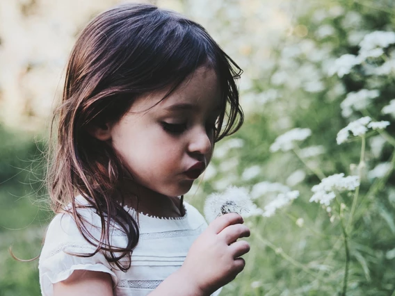 A young girl smells some flowers